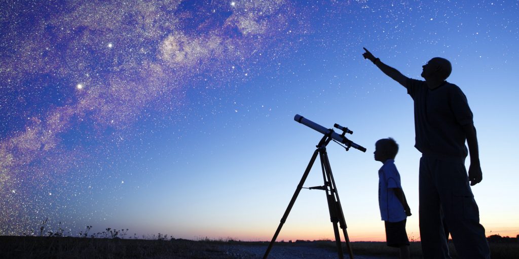 Man showing milky way to little boy, telescope